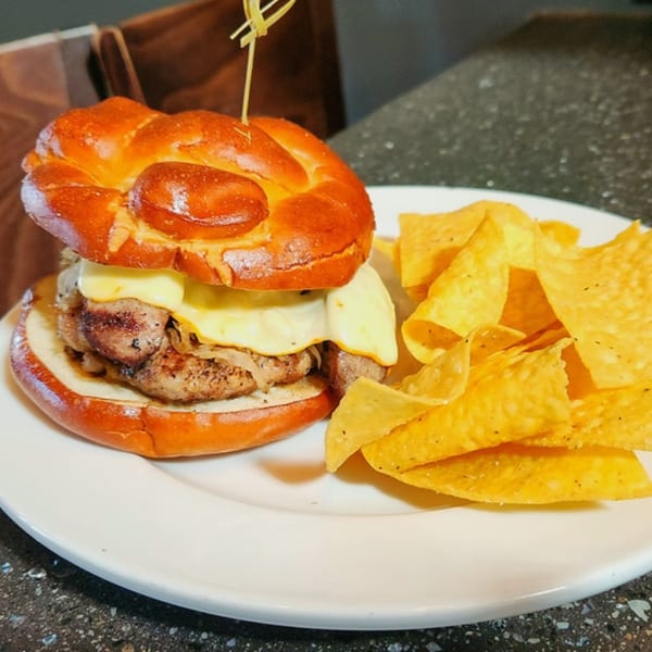 A Wasena City Tap Room & Grill burger with melted cheese and grilled onions, served with tortilla chips.