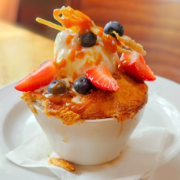 A Wasena City Tap Room & Grill dessert with ice cream, berries, and caramel in a white bowl.