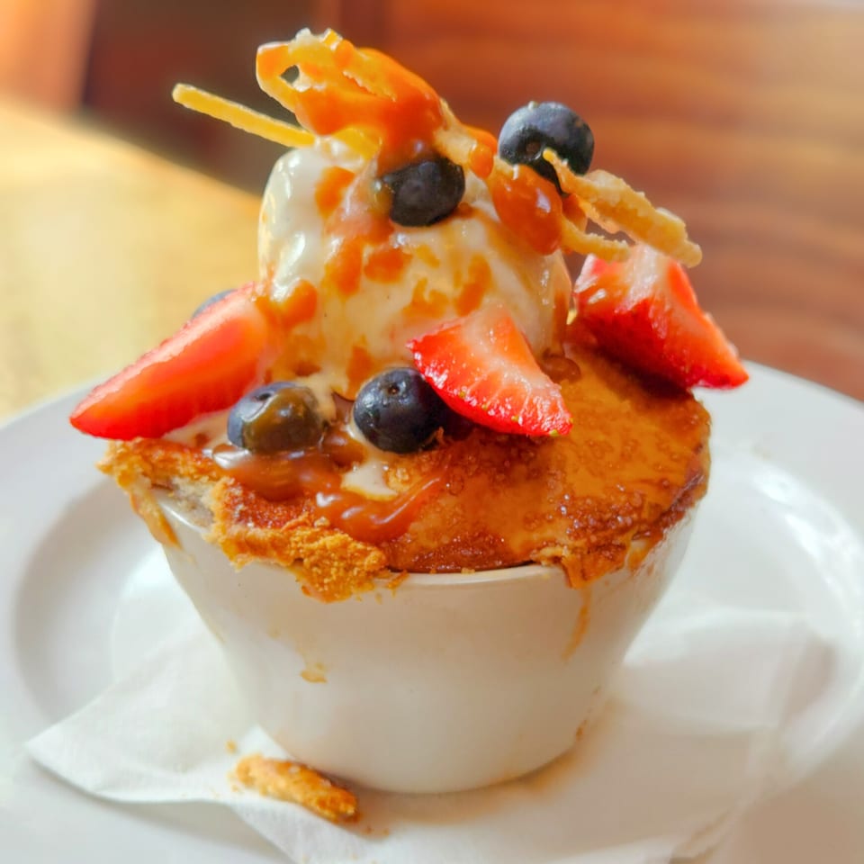 A Wasena City Tap Room & Grill dessert with ice cream, berries, and caramel in a white bowl.